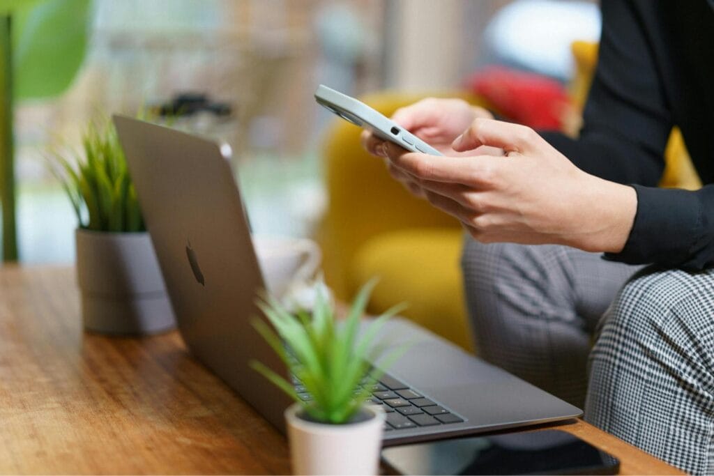 Person using a laptop and phone while reading guidance on building insurance for leaseholders