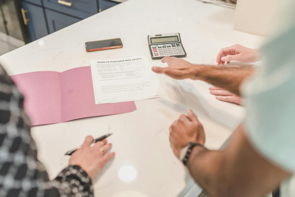 Hands reviewing property management paperwork with a calculator when assessing managing agent costs and compliance risks